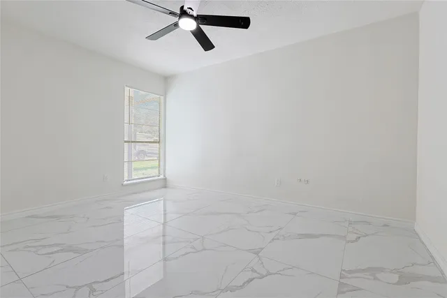 an empty room with windows and fan