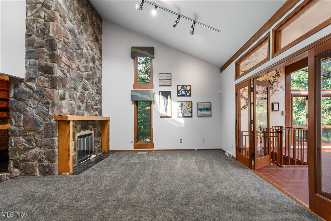 2317 Raintree Street Northeast Canton, OH 44705 - Photo 9 of 40 Unfurnished living room featuring carpet floors, healthy amount of natural light, high vaulted ceiling, rail lighting, and a stone fireplace