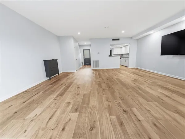 a view of empty room with wooden floor and windows