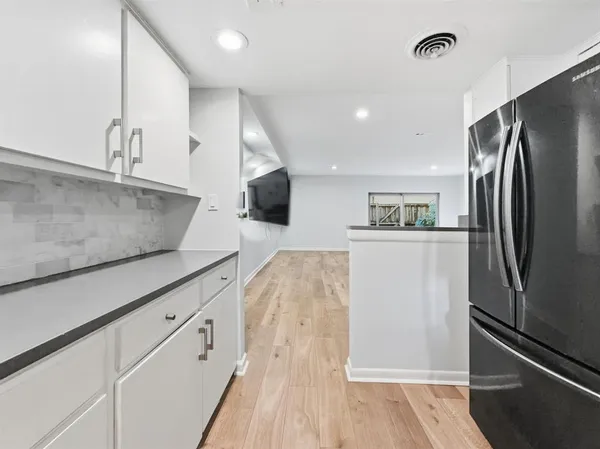 a kitchen with stainless steel appliances granite countertop a refrigerator a sink and white cabinets