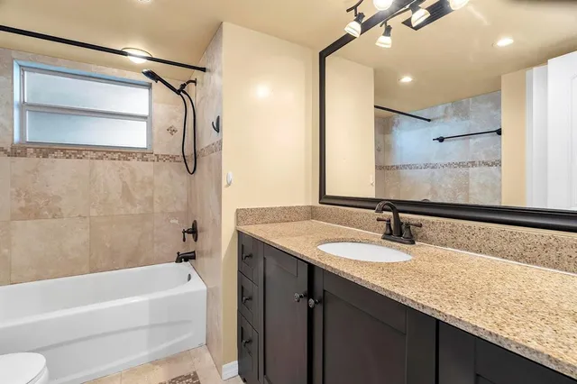 a bathroom with a granite countertop sink toilet and shower