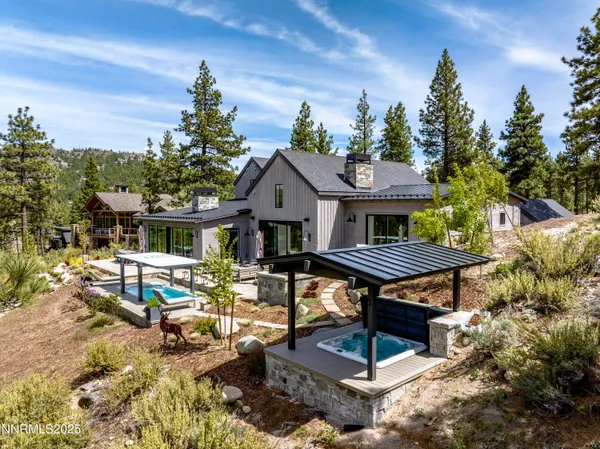 a view of house with backyard outdoor seating and trees in the background