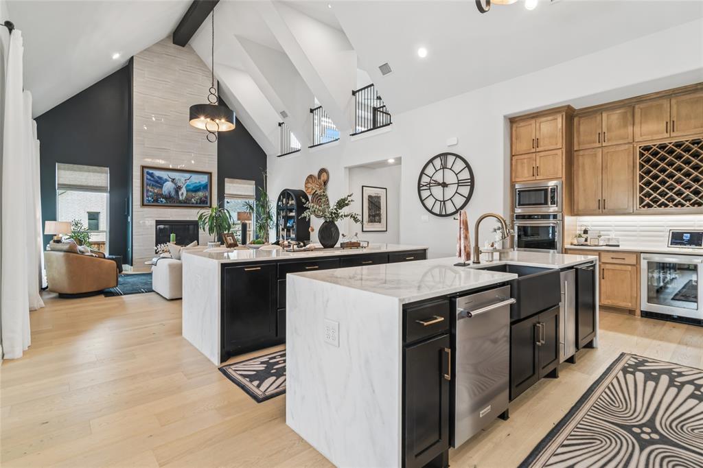 1920 Lotus Court Haslet, TX 76052 - Photo 10 of 40 2 oversized islands with waterfall granite, both allow for bar seating. Dual pullout garbage cans, ice maker, apron front large single sink, beverage frig at drink bar with wine storage above. Double oven.