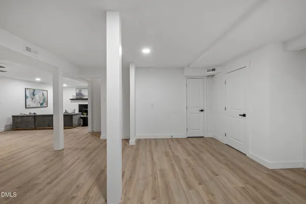 an empty room with wooden floor closet and windows
