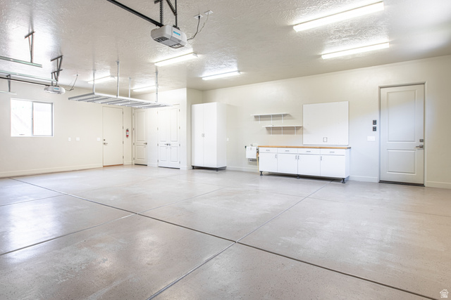 322 340 E Street Ivins, UT 84738 - Photo 46 of 61 Spacious garage featuring concrete flooring, overhead storage racks, built-in white cabinetry with a wood-finish countertop, and multiple overhead fluorescent light fixtures