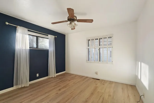 a view of an empty room with a window and wooden floor