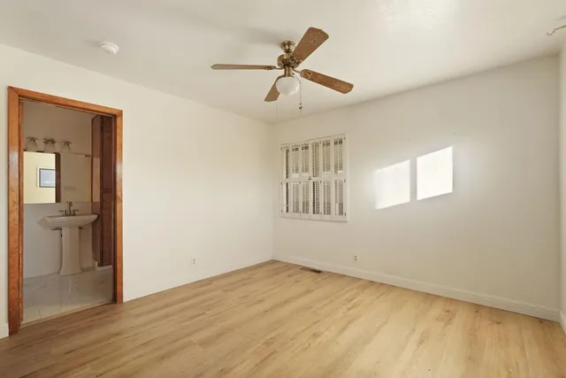 a view of empty room with wooden floor and ceiling fan