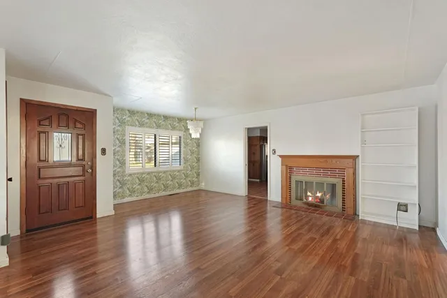 an empty room with wooden floor fireplace and windows
