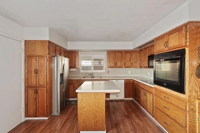 a kitchen with granite countertop a refrigerator and wooden cabinets