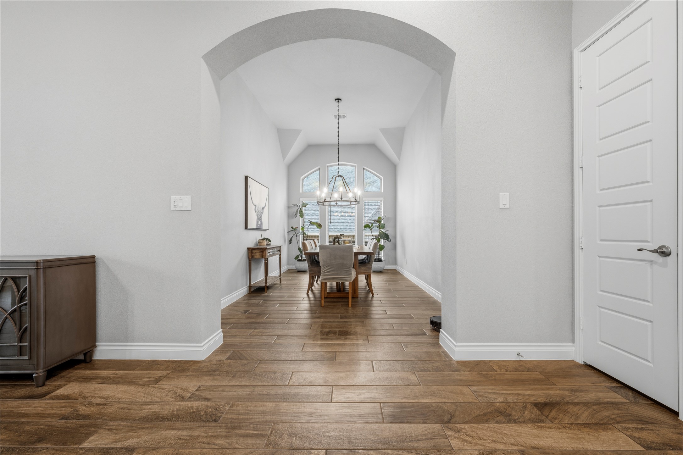 140 Catani Loop Georgetown, TX 78628 - Photo 19 of 36 Archways lead to a dining space illuminated by a chandelier and abundant natural light from the expansive window wall.