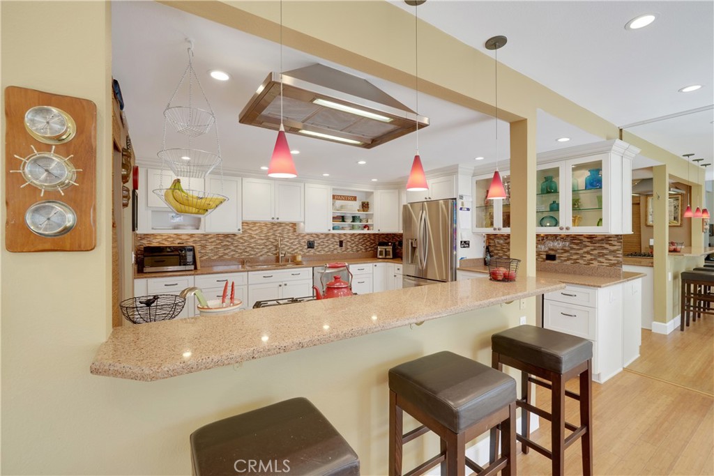 2422 Miseno Way Costa Mesa, CA 92627 - Photo 15 of 40 a kitchen with stainless steel appliances kitchen island granite countertop a table and chairs in it