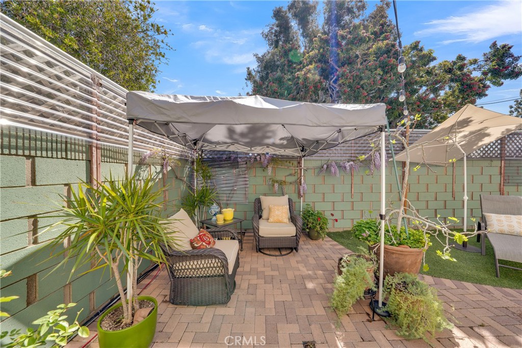 2422 Miseno Way Costa Mesa, CA 92627 - Photo 22 of 40 a view of a patio with table and chairs potted plants and a palm tree