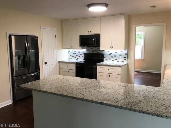 2824 Montclair Road Winston-Salem, NC 27106 - Photo 6 of 30 Kitchen features granite countertops, new cabinets, tile backsplash, new black SS appliances, under cabinet lighting, and a spacious pantry!