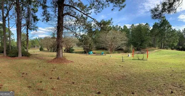 a view of house with backyard and chairs