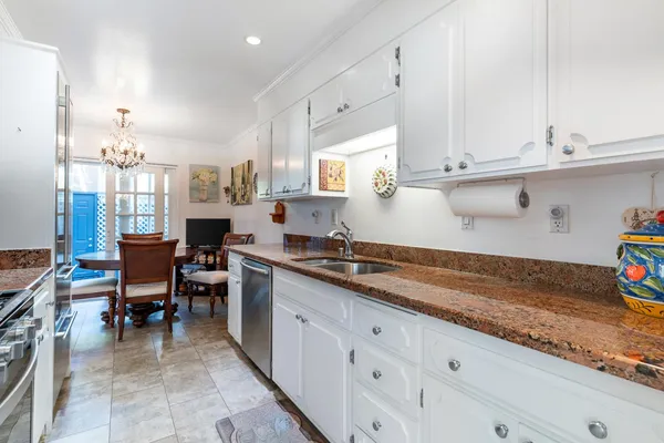a kitchen with stainless steel appliances granite countertop a stove top oven a sink a dining table and chairs