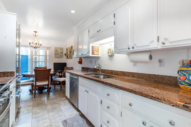 a kitchen with stainless steel appliances granite countertop a stove top oven a sink a dining table and chairs