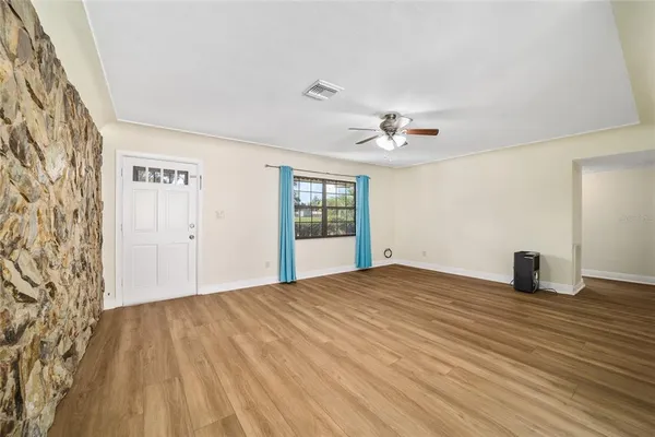 a view of a room with wooden floor and a ceiling fan
