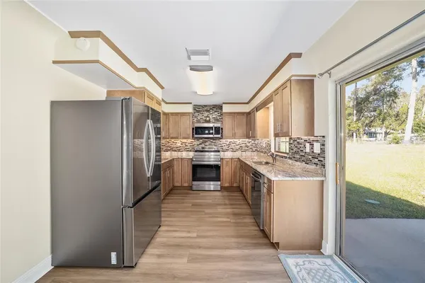 a kitchen with stainless steel appliances granite countertop a refrigerator a sink dishwasher a stove and white countertops with wooden floor