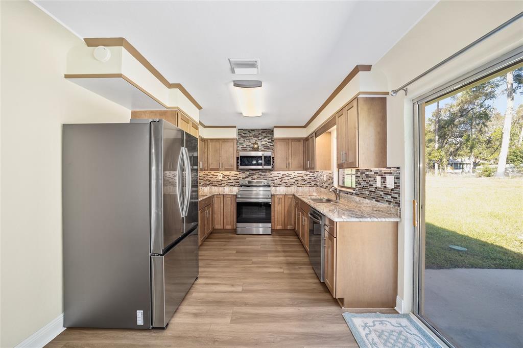 5201 East Jasmine Lane Inverness, FL 34453 - Photo 25 of 50 a kitchen with stainless steel appliances granite countertop a refrigerator a sink dishwasher a stove and a dining table with wooden floor