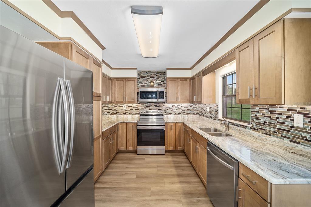 5201 East Jasmine Lane Inverness, FL 34453 - Photo 26 of 50 a kitchen with stainless steel appliances granite countertop a refrigerator a sink dishwasher a stove and white countertops with wooden floor