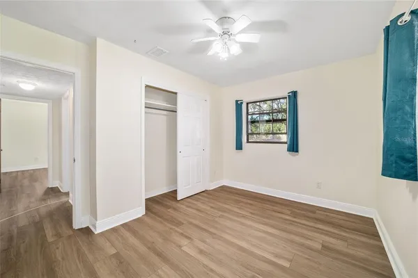 an empty room with wooden floor and a ceiling fan