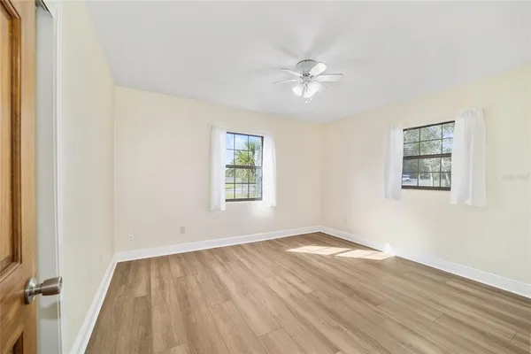 an empty room with wooden floor and fan