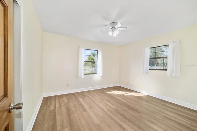 an empty room with wooden floor and fan