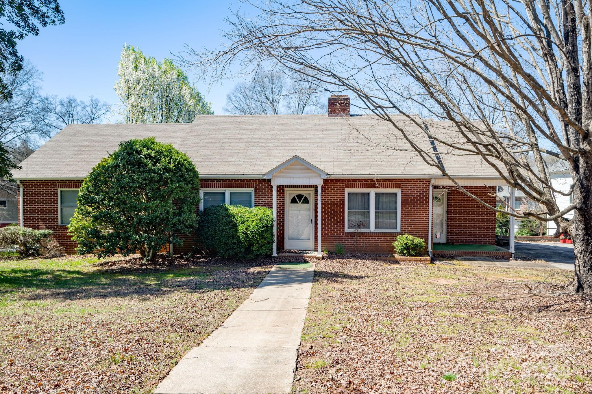a front view of a house with a yard and potted plants