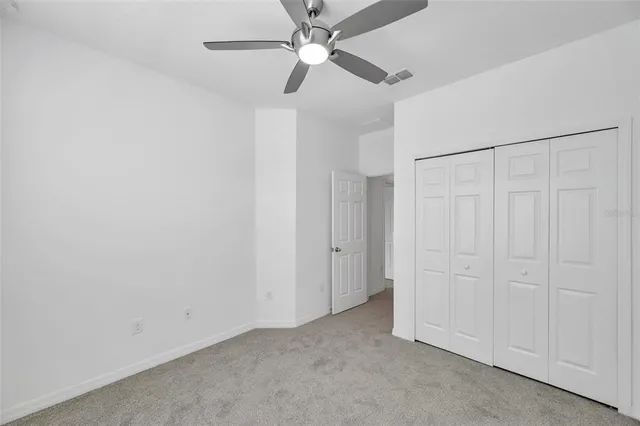 an empty room with closet and a ceiling fan