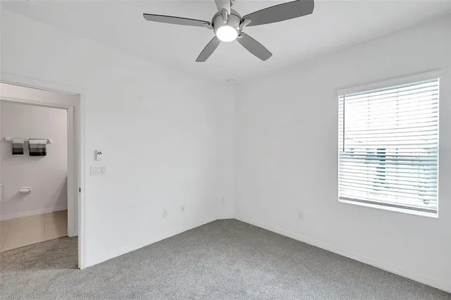 an empty room with a window and a fan