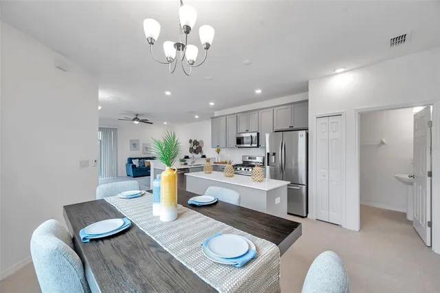 a kitchen with a dining table chairs stainless steel appliances and cabinets