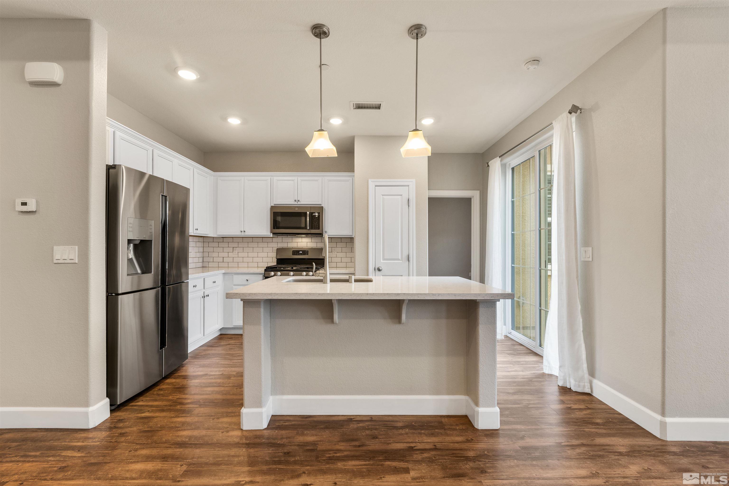 1945 Sea Horse Road, Unit A Reno, NV 89521 - Photo 9 of 25 a kitchen with stainless steel appliances granite countertop a refrigerator a sink dishwasher a stove and white cabinets with wooden floor
