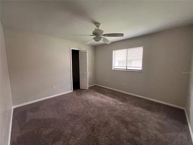 an empty room with windows and ceiling fan