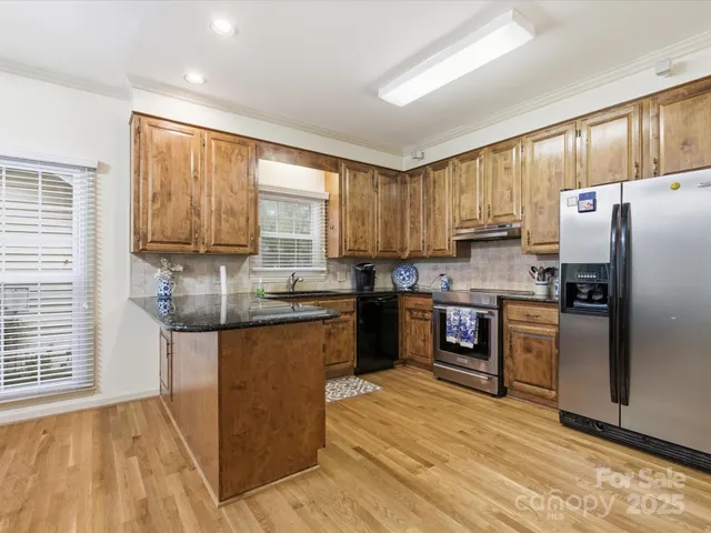 a kitchen with stainless steel appliances granite countertop a refrigerator sink and stove