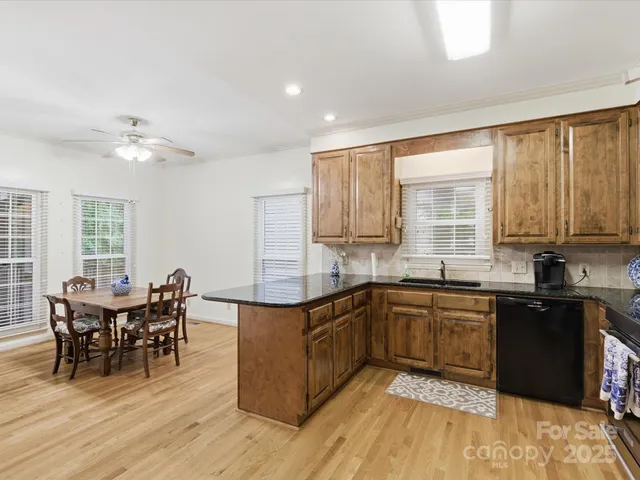 a kitchen with stainless steel appliances granite countertop wooden cabinets a dining table and chairs