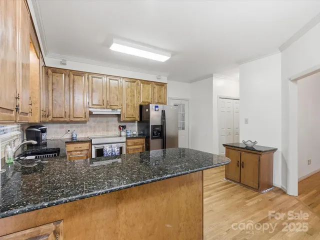 a kitchen with stainless steel appliances granite countertop a sink refrigerator and cabinets