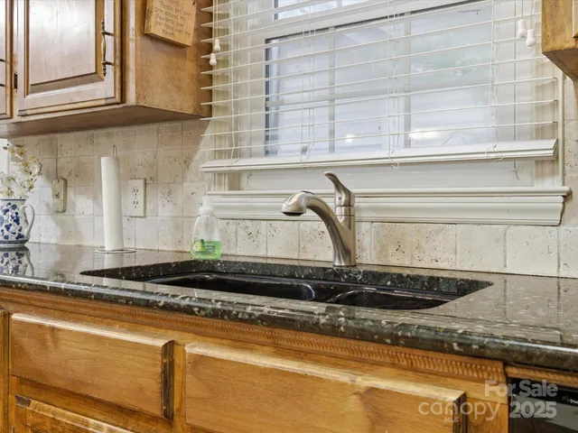 a close view of a sink a granite counter top a sink and a window