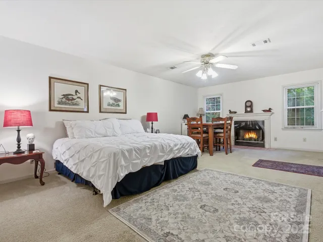 a spacious bedroom with a large bed a chandelier and dresser