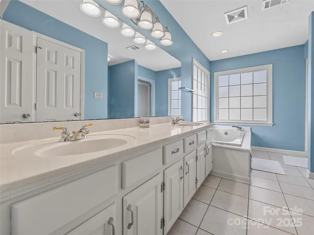 a spacious bathroom with a double vanity sink mirror and bathtub