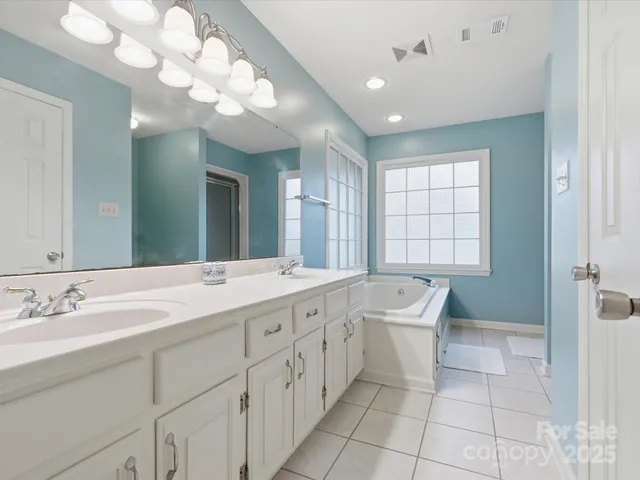 a spacious bathroom with a double vanity sink a mirror and a bathtub