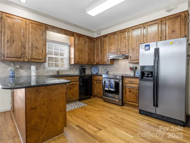 a kitchen with granite countertop a refrigerator stove top oven and sink