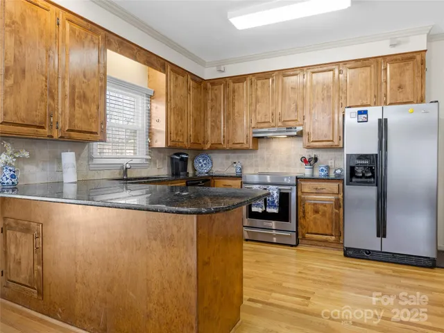 a kitchen with granite countertop a refrigerator a sink a stove and cabinets