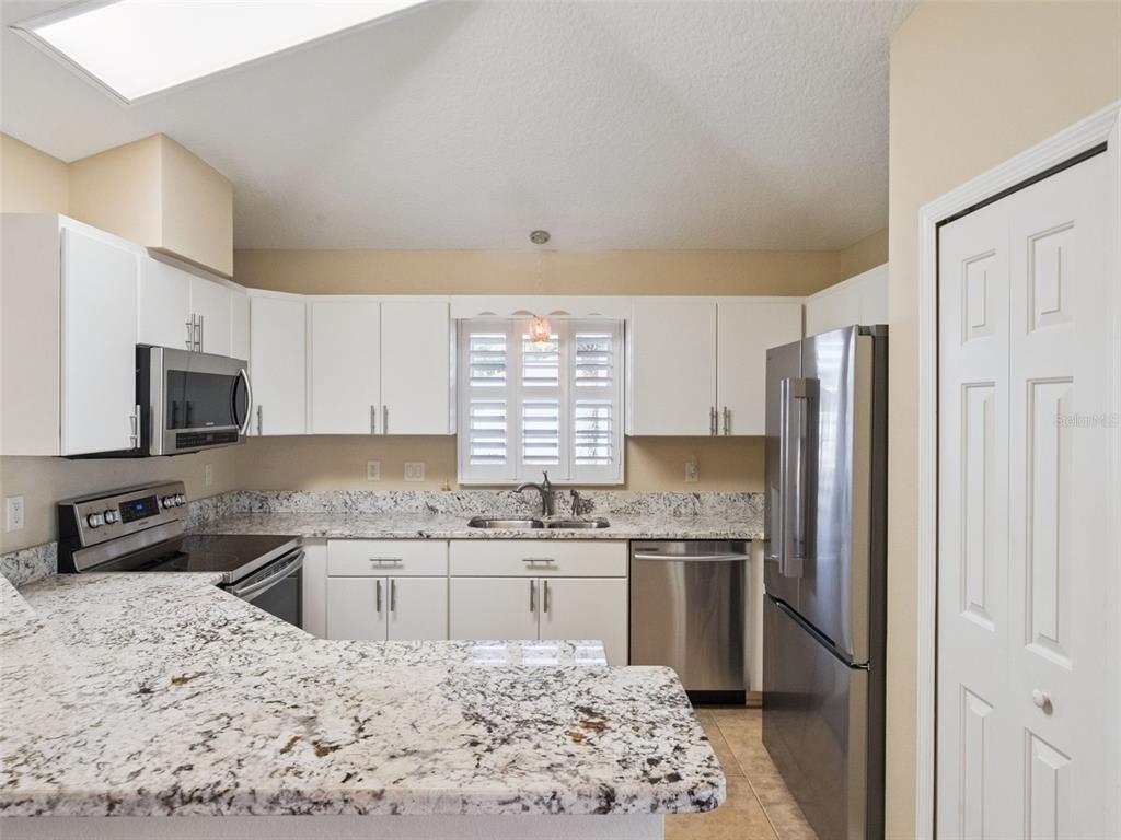 20642 Prince Ranier Place Leesburg, FL 34748 - Photo 10 of 59 a kitchen with stainless steel appliances kitchen island granite countertop a sink stove and refrigerator