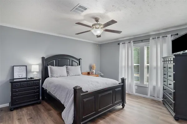 a bedroom with a bed a flat tv screen and dresser