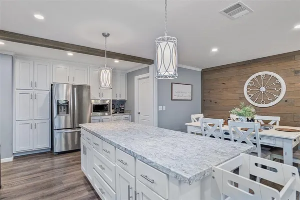 a kitchen with granite countertop a table chairs refrigerator and microwave