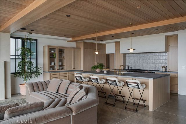 a living room with stainless steel appliances granite countertop lots of white furniture a window and a sink