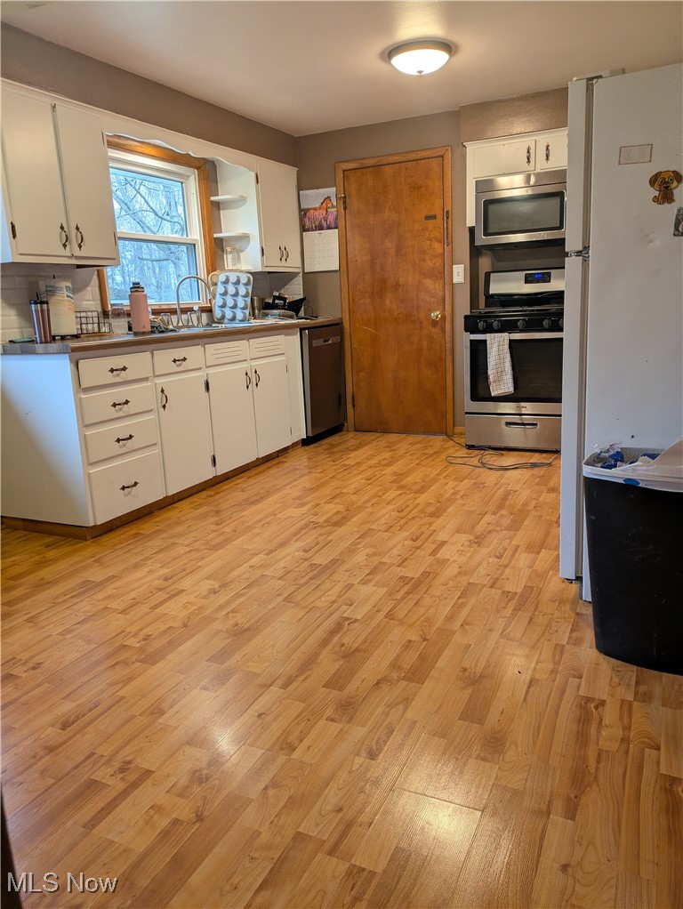 9581 Colton Road Windham, OH 44288 - Photo 8 of 26 Kitchen with light wood finished floors, stainless steel appliances, open shelves, a sink, and white cabinetry