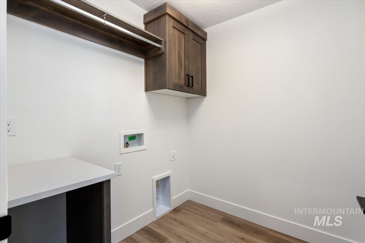 768 South Calhoun Lane Star, ID 83669 - Photo 30 of 36 Dedicated laundry area featuring wood-finish flooring, white walls, and a built-in wood-look cabinet with matte black hardware