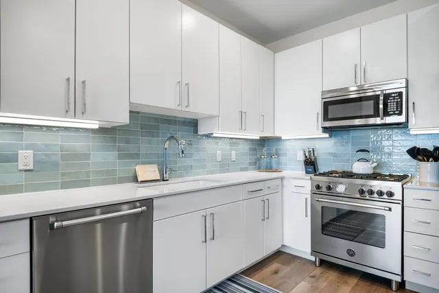 a kitchen with white cabinets and stainless steel appliances