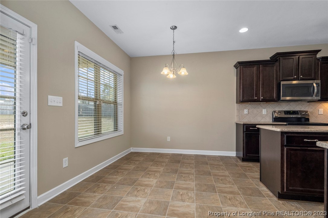 152 Copper Loop Sanford, NC 27332 - Photo 22 of 50 a kitchen with kitchen island granite countertop a stove a sink and a microwave